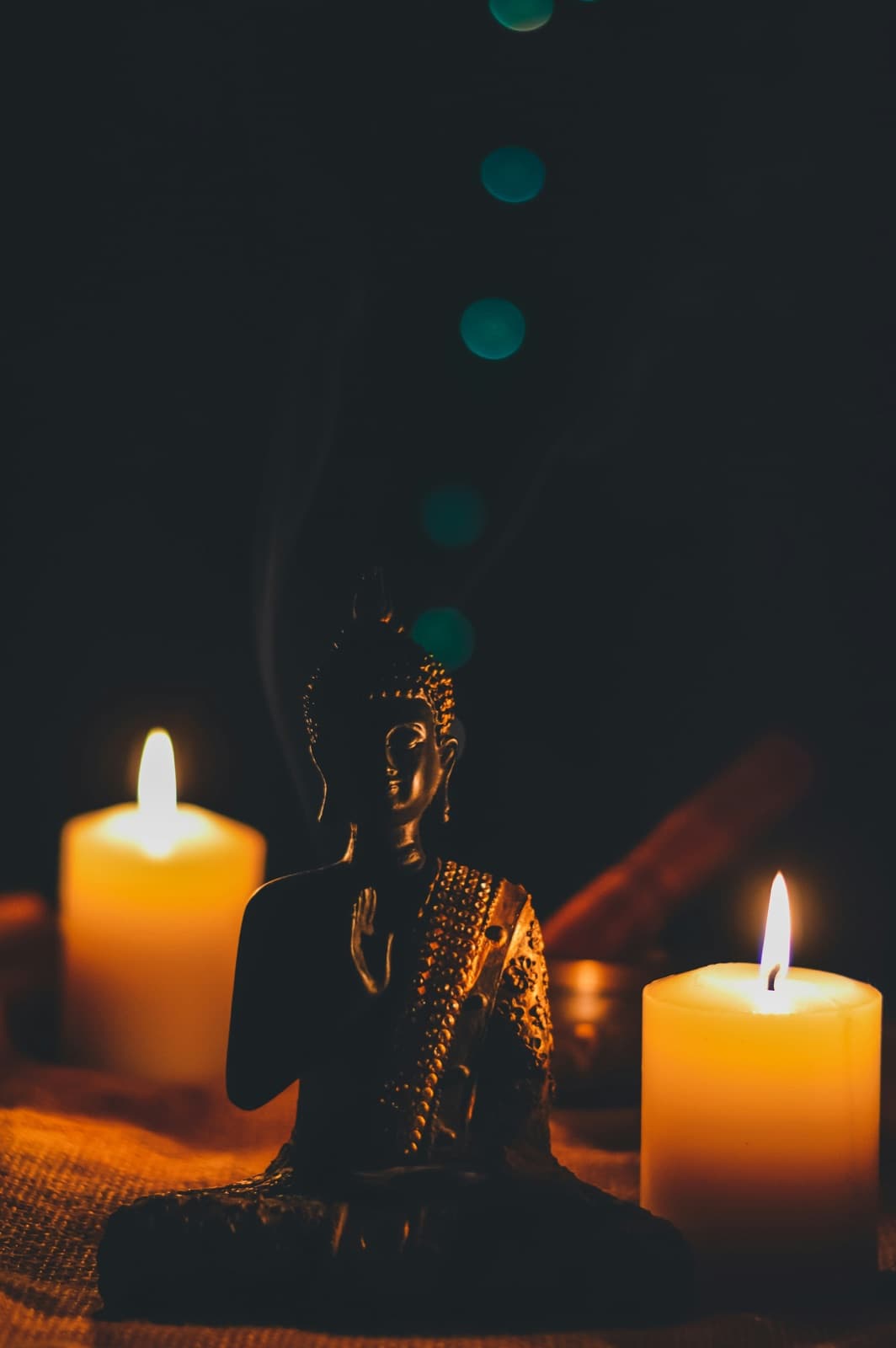 Candles surrounding a small Buddha statue in a quiet setting